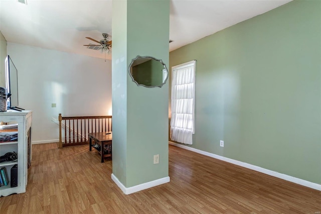 spare room featuring light wood finished floors, ceiling fan, and baseboards