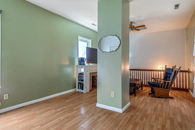 living area with baseboards, ceiling fan, visible vents, and light wood finished floors