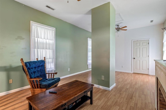 living area featuring light wood-style floors, ceiling fan, and visible vents