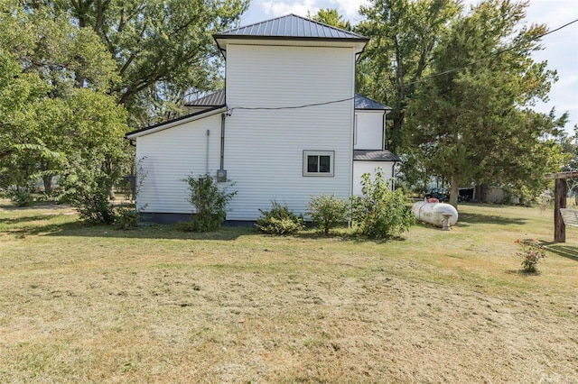 view of side of property with metal roof and a yard