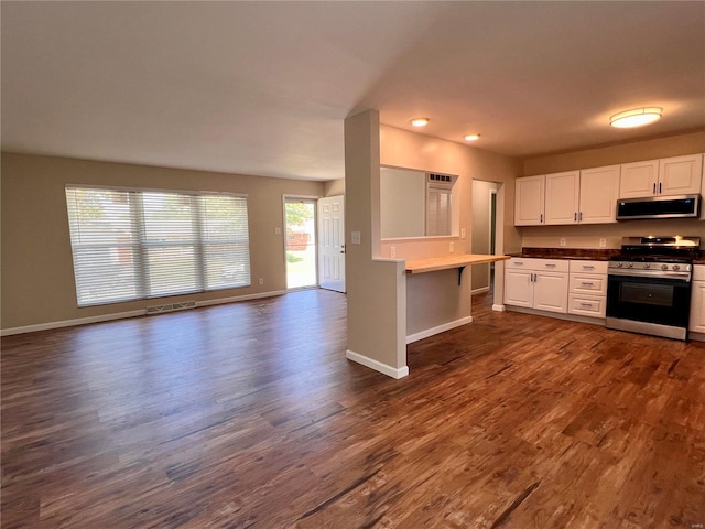 kitchen featuring white cabinets, gas range, dark wood-type flooring, and a healthy amount of sunlight