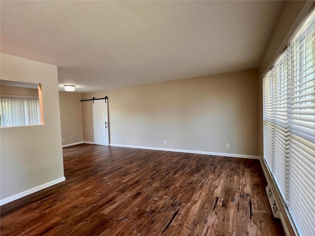 spare room featuring a barn door and dark hardwood / wood-style flooring