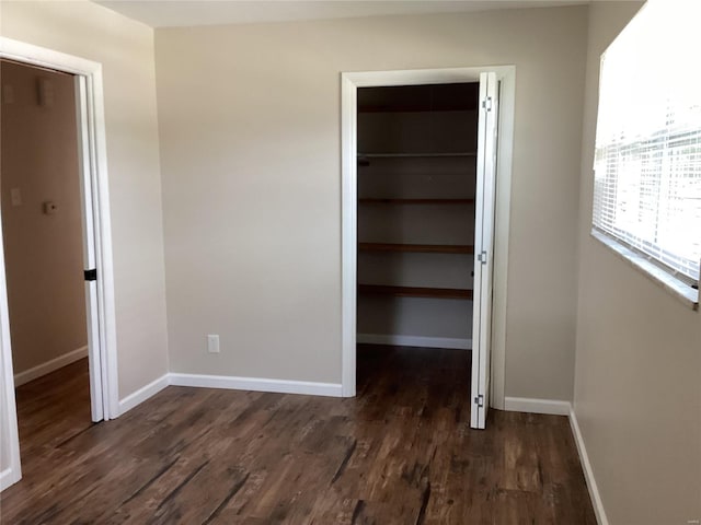 interior space featuring a walk in closet, a closet, and dark wood-type flooring