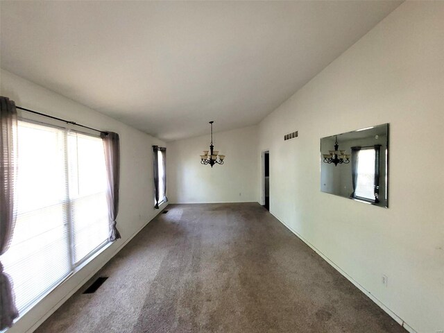 carpeted spare room featuring lofted ceiling, a chandelier, and a wealth of natural light