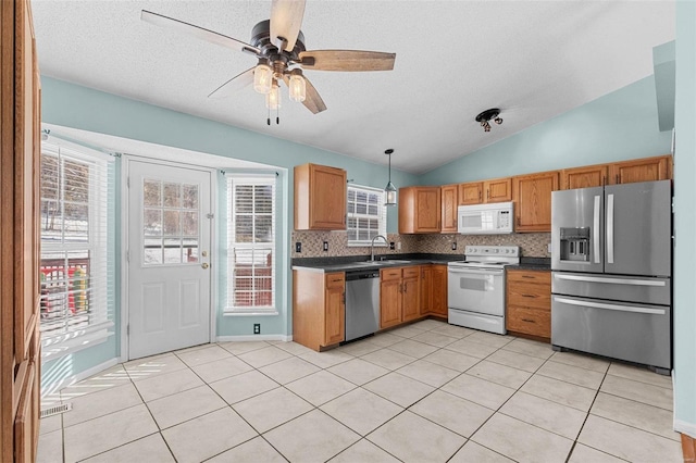 kitchen with appliances with stainless steel finishes, dark countertops, pendant lighting, and tasteful backsplash