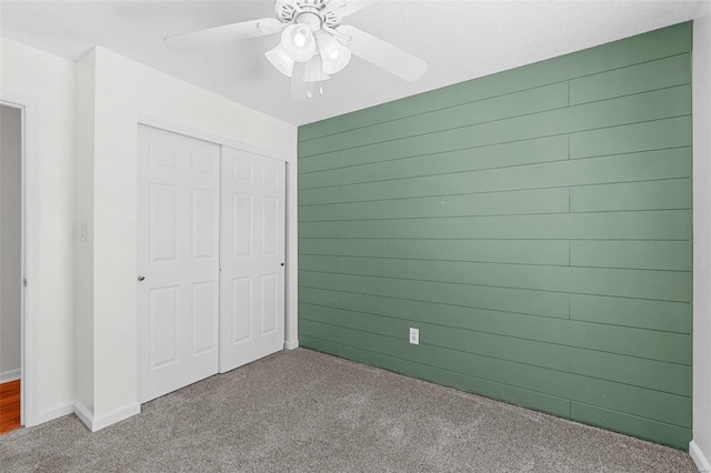 unfurnished bedroom featuring a closet, carpet, and wooden walls