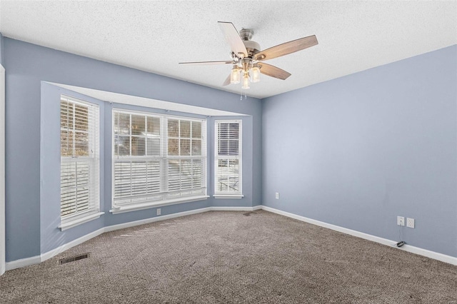 unfurnished room with carpet, visible vents, a textured ceiling, and baseboards