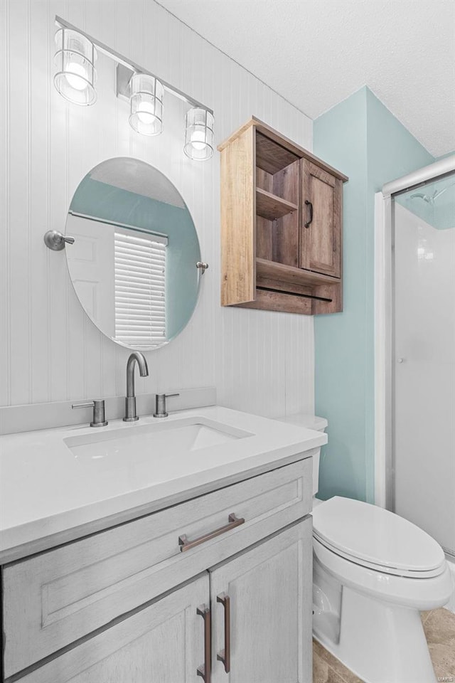 full bath with a stall shower, vanity, toilet, and a textured ceiling