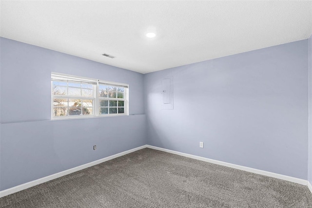 empty room with carpet, visible vents, a textured ceiling, and baseboards