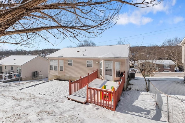 snow covered house featuring fence and a wooden deck