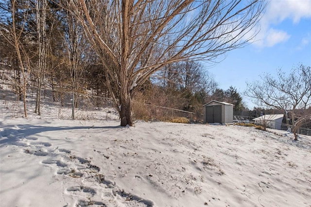 yard covered in snow featuring a storage shed, an outbuilding, and fence