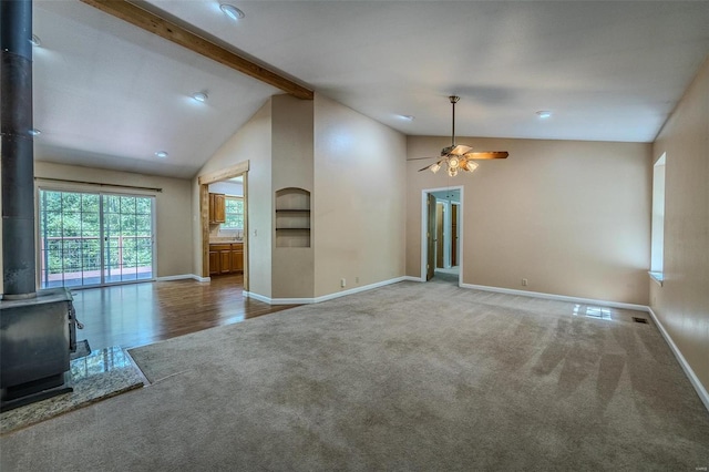 unfurnished living room featuring a wood stove, beam ceiling, high vaulted ceiling, hardwood / wood-style flooring, and ceiling fan