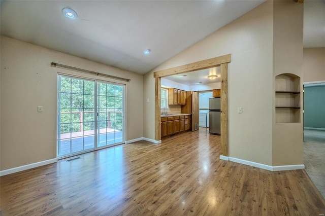 unfurnished living room with built in shelves, high vaulted ceiling, light hardwood / wood-style floors, and sink