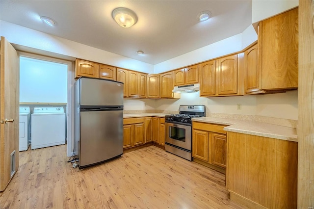 kitchen with light wood-type flooring, appliances with stainless steel finishes, and washer and clothes dryer