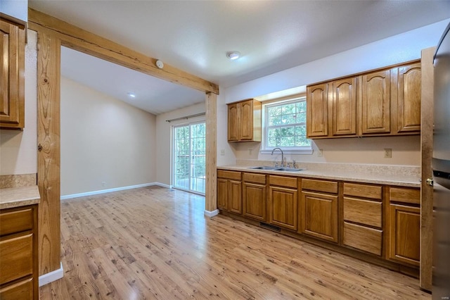 kitchen featuring lofted ceiling with beams, sink, and light hardwood / wood-style floors