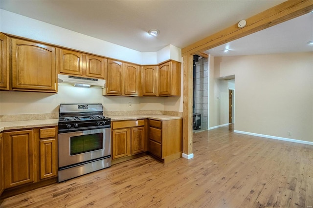 kitchen featuring stainless steel gas stove, vaulted ceiling, and light hardwood / wood-style floors