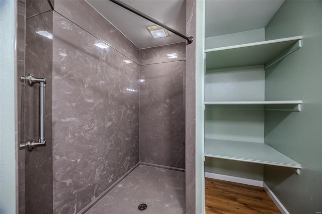 bathroom with wood-type flooring and a tile shower