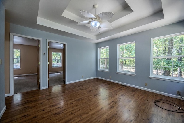 unfurnished room with a raised ceiling, ceiling fan, and dark wood-type flooring