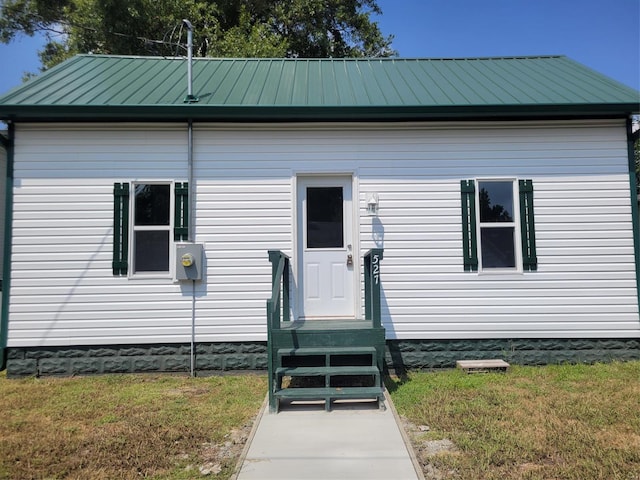 view of front facade with a standing seam roof, metal roof, and a front yard