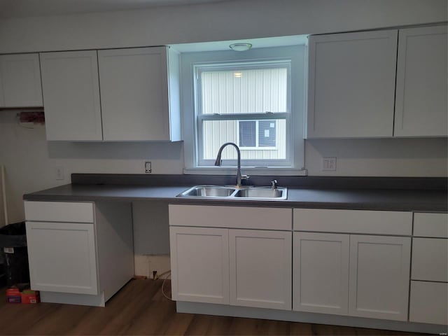 kitchen featuring dark countertops, a sink, dark wood finished floors, and white cabinets