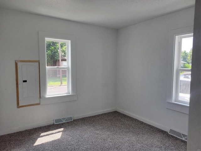 carpeted empty room featuring electric panel, visible vents, and baseboards