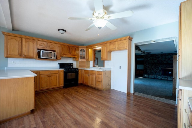 kitchen featuring black gas stove, stainless steel microwave, dark wood-type flooring, and ceiling fan