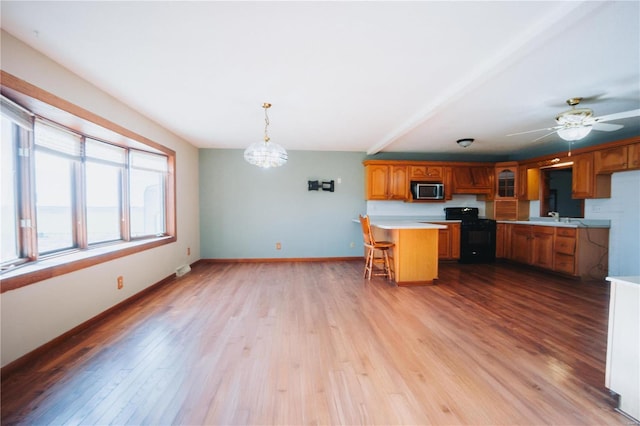 kitchen featuring a kitchen bar, light hardwood / wood-style floors, black range with electric stovetop, and hanging light fixtures