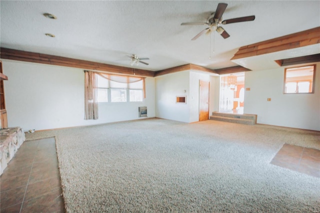 unfurnished living room with plenty of natural light, ceiling fan, a textured ceiling, and dark carpet