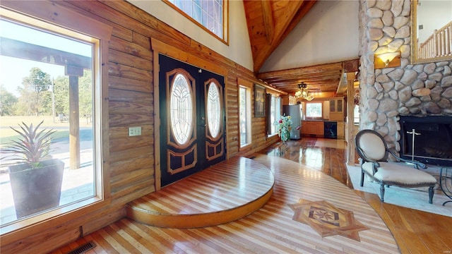 foyer with wood ceiling, ceiling fan, hardwood / wood-style flooring, high vaulted ceiling, and a stone fireplace