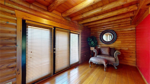 sitting room with beam ceiling, light hardwood / wood-style flooring, wood ceiling, and log walls