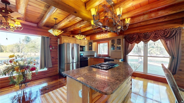 kitchen featuring a kitchen island, beam ceiling, a healthy amount of sunlight, black appliances, and light wood-type flooring