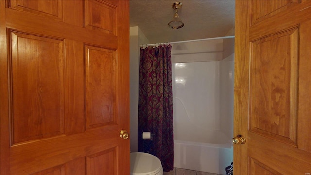 bathroom featuring toilet, a textured ceiling, and shower / tub combo with curtain