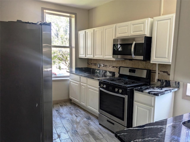 kitchen with white cabinetry, stainless steel appliances, decorative backsplash, and light wood-type flooring