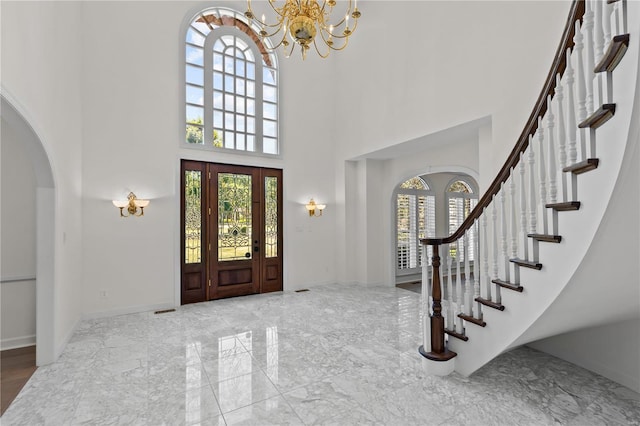 tiled entrance foyer featuring a wealth of natural light, a high ceiling, and a notable chandelier