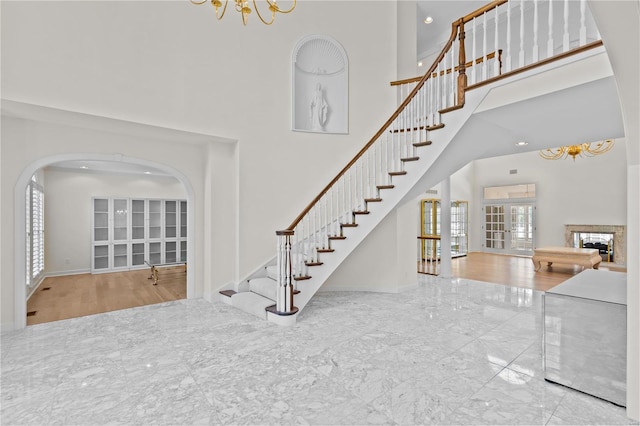 stairs featuring a towering ceiling, wood-type flooring, and a chandelier