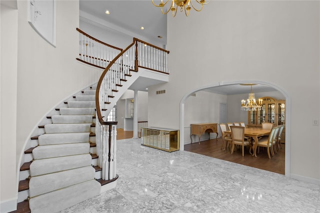 stairway featuring a towering ceiling, a notable chandelier, crown molding, and hardwood / wood-style floors