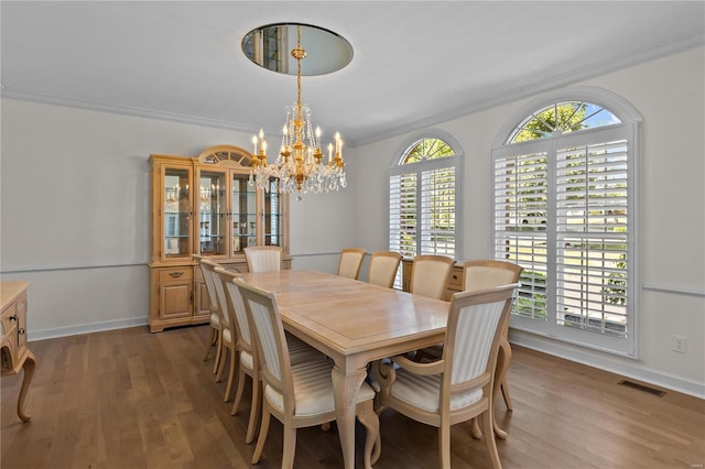 dining area with hardwood / wood-style flooring, crown molding, a healthy amount of sunlight, and a chandelier