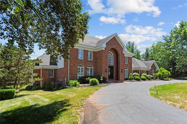 colonial inspired home with a front lawn and central air condition unit