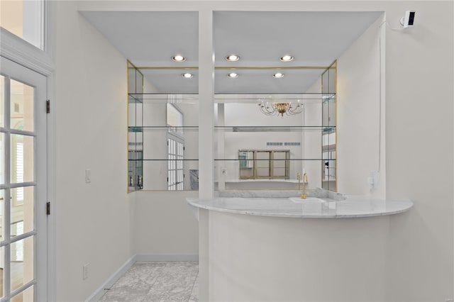 bar with light tile patterned floors, light stone counters, and a healthy amount of sunlight