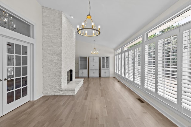 interior space with vaulted ceiling, a chandelier, and a stone fireplace