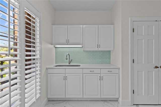 kitchen with sink, white cabinets, light tile patterned flooring, and backsplash