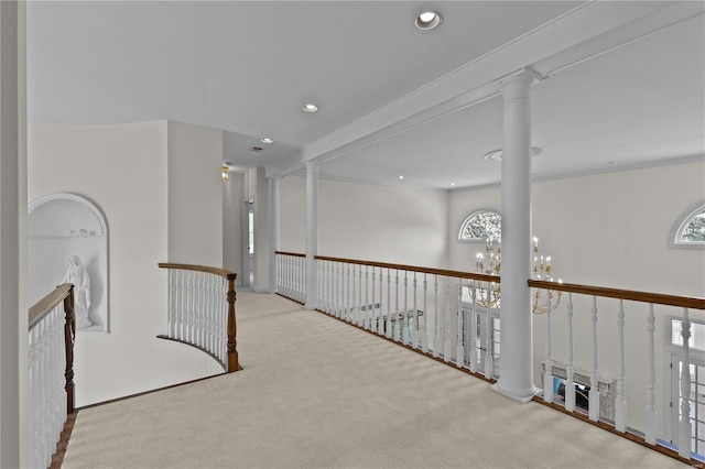 hall with crown molding, a chandelier, light colored carpet, and ornate columns