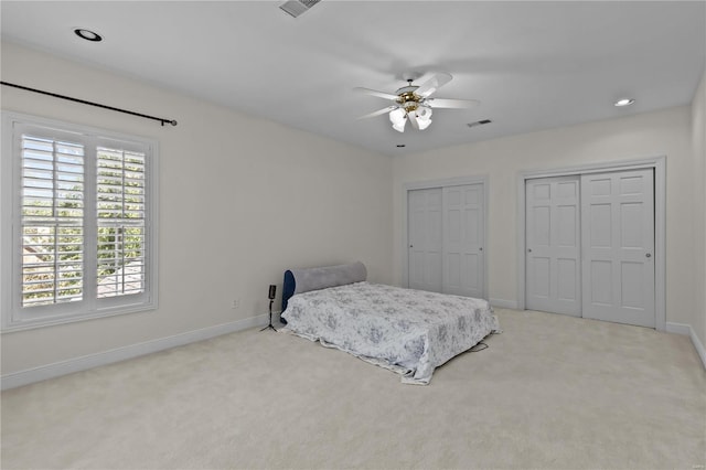 carpeted bedroom featuring ceiling fan and multiple closets