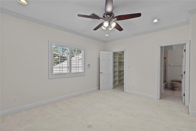 unfurnished bedroom with light colored carpet, a spacious closet, ensuite bath, and ceiling fan