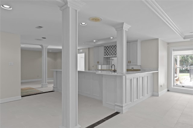 kitchen with sink, kitchen peninsula, decorative columns, and light tile patterned floors