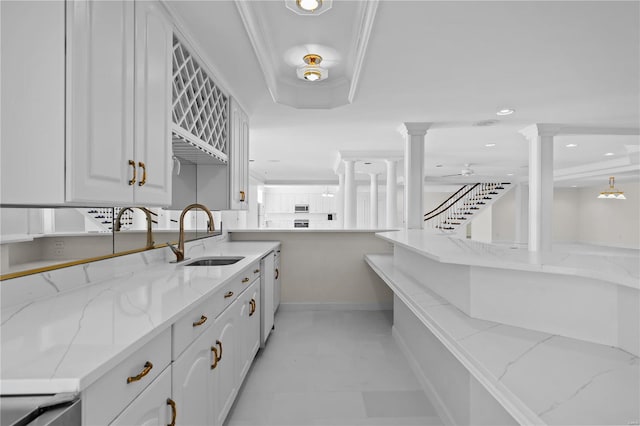 kitchen featuring sink, light stone counters, white cabinets, light tile patterned floors, and kitchen peninsula