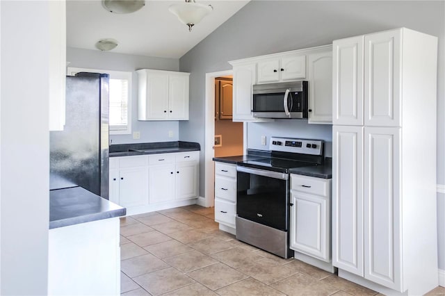 kitchen with light tile patterned floors, white cabinetry, stainless steel appliances, and lofted ceiling