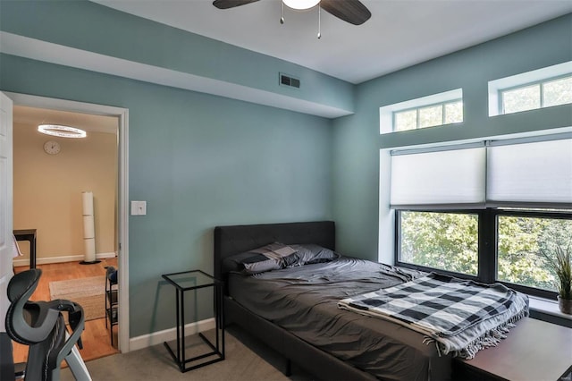 bedroom with ceiling fan, light hardwood / wood-style floors, white fridge, and multiple windows