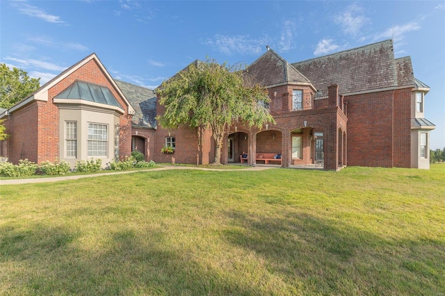 tudor house featuring a front lawn and a patio area