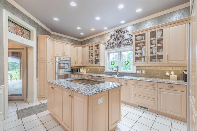 kitchen with a center island, light stone countertops, crown molding, light tile patterned flooring, and stainless steel appliances